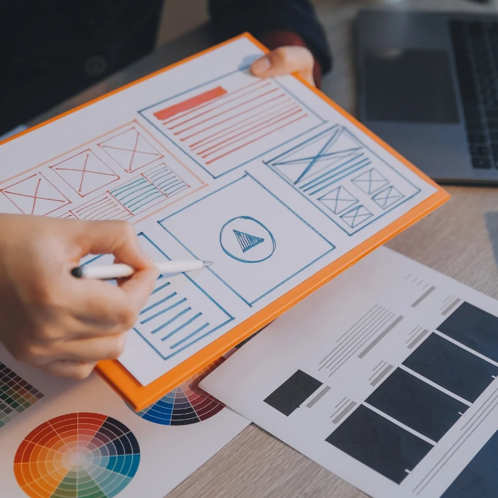 Designer draws website wireframes on paper with pen and ruler for Norwalk web design