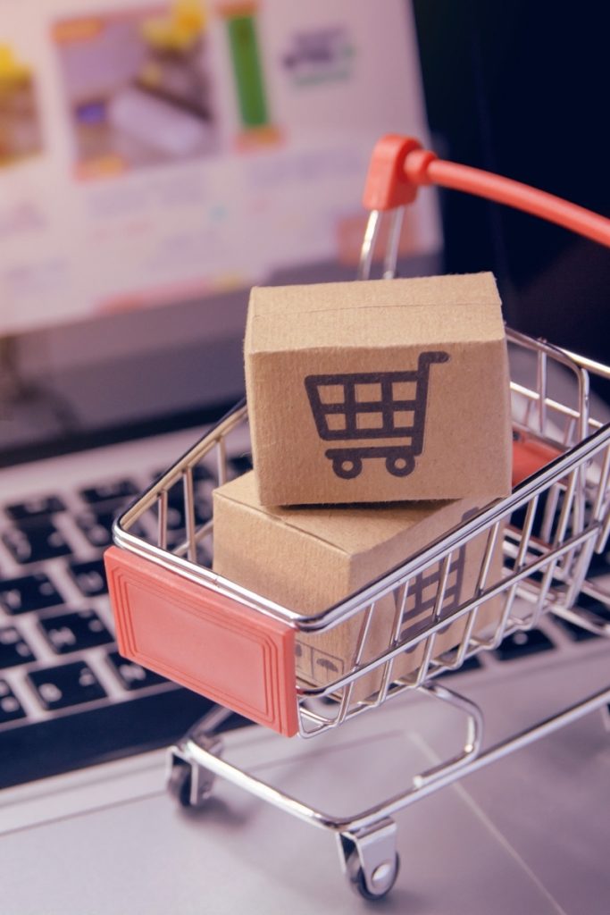 Small shopping cart and parcels sit on a laptop keyboard for Norwalk e commerce