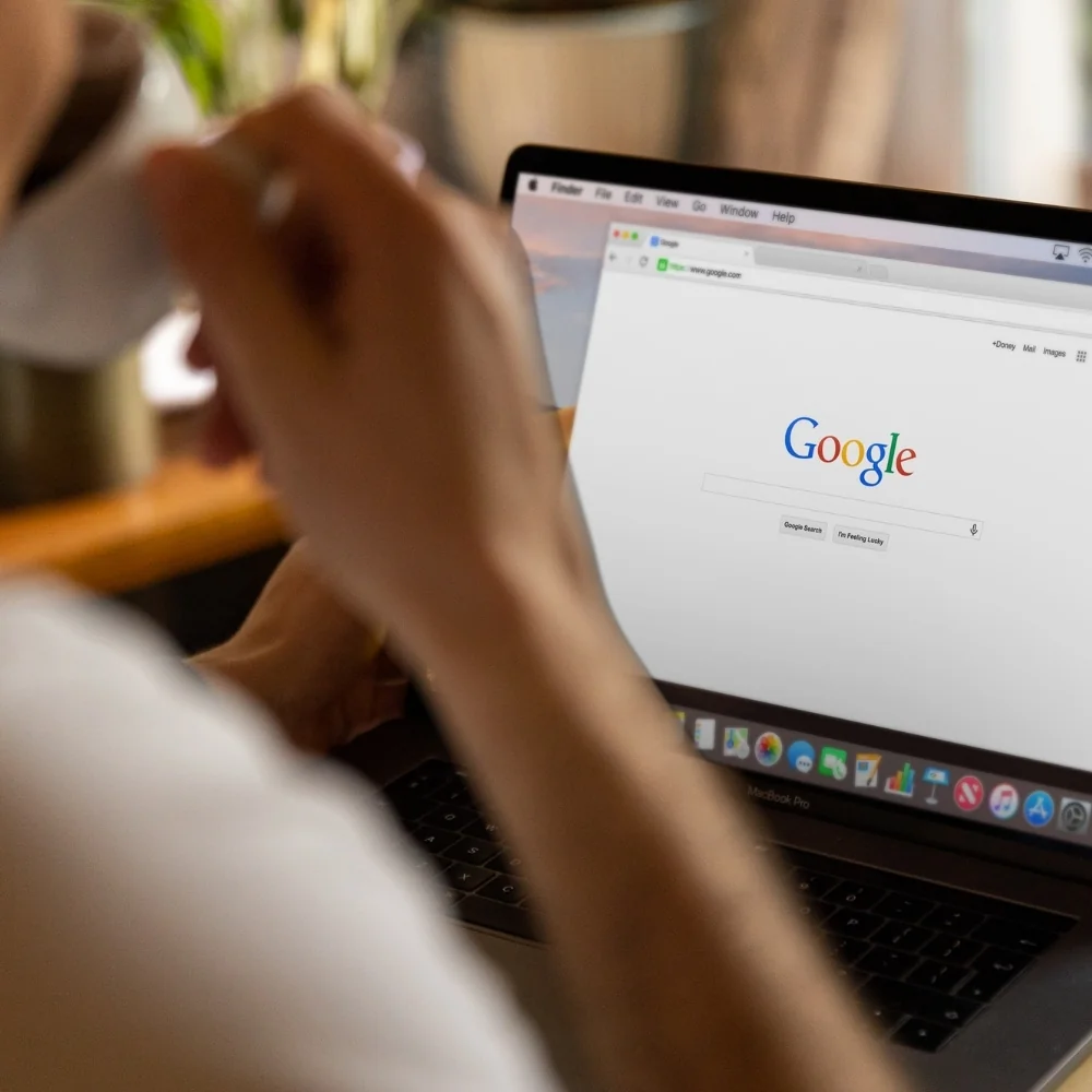 Person uses a laptop with a Google search page open for Norwalk SEO.